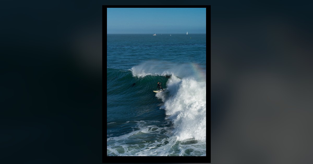 Surfer carving across the dark face of a breaking Pacific wave